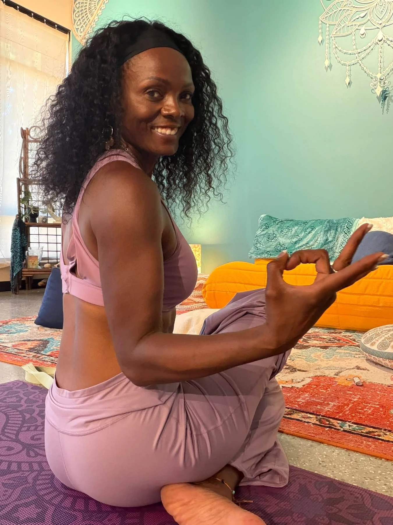 Dr. Danielle Nicole smiling while seated on a purple yoga mat at Calm Soul Studio.